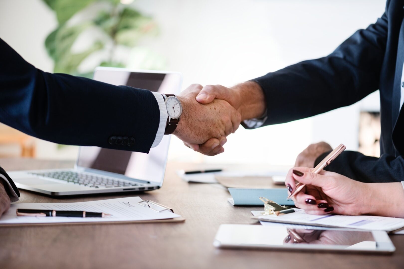 Business handshake over desk with documents