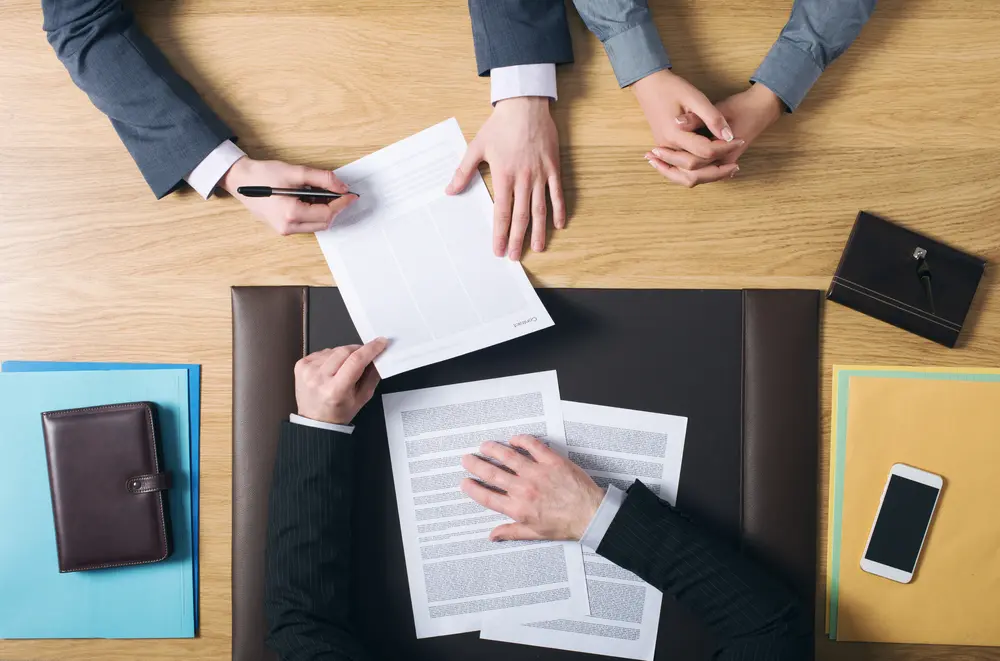Couple signing marriage documents Business man and woman sitting at the lawyers's desk and signing important documents, hands top view, unrecognizable people